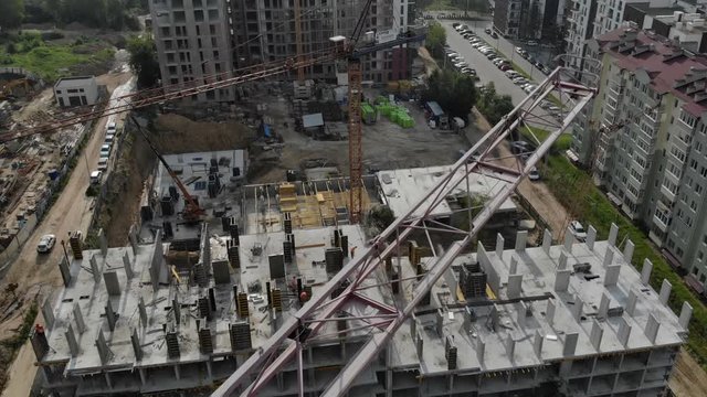 Flight near the unfinished monolithic house. Construction crane near the construction site. Top view of the construction