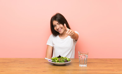 Young woman with a salad with thumbs up because something good has happened