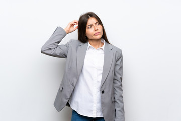 Young business woman over isolated white background having doubts while scratching head