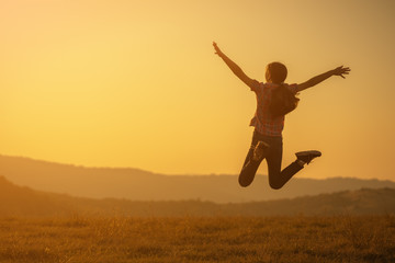 Happy child jumping in nature in sunset.
