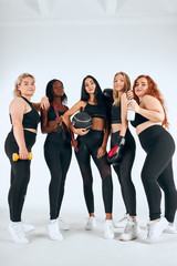 Fototapeta na wymiar Young attractive girls in black sportswear stand together, promote sport life, healthy lifestyle concept, sport