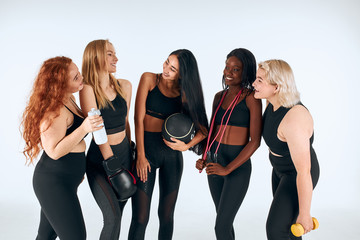 Smiling women in black sportive clothes laughing, look at each other, promote healthy lifestyle, people relationship.