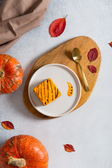 Homemade pumpkin cheesecake pie recipe with cinnamon on white table with pumpkins and autumn leaves on the background. Halloween party traditional dessert. Thanksgiving, menu. Top view, copy space