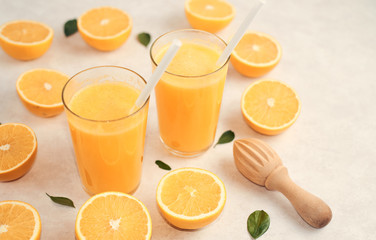 fresh orange in a glass with a straw on a neutral background with cut oranges on the table