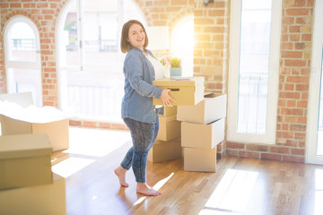 Fototapeta na wymiar Young beautiful plus size woman moving to a new house, holding cardboxes smiling very happy for new apartment