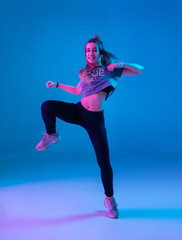 Young stylish girl dancing zumba in the Studio on a colored neon background. Dance poster design.