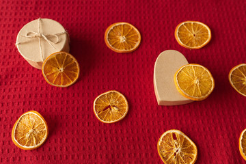 Craft box and dried oranges on a red background with copy space. Healthy sweets concept. Flat lay
