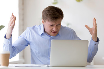Angry middle aged businessman looking at laptop screen.