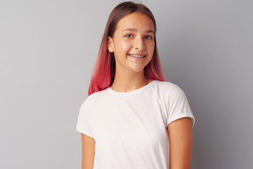 Young girl teenager with pink hair happy and smiling over gray background