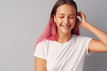 Young girl teenager with pink hair happy and smiling over gray background