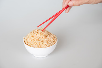 instant noodle and red chopstick with hand holding in white background