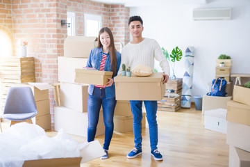 Fototapeta na wymiar Beautiful young asian couple looking happy holding cardboard boxes, smiling excited moving to a new home