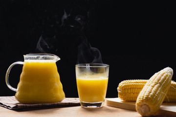 The steam from a jug and a glass of corn milk on black background, Warm drinks make good healthy,Prevent eye disease, High in fiber, Many vitamins and anti-cancer agents, Made from maize.