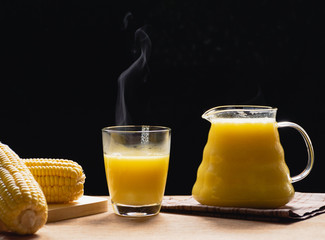 The steam from a jug and a glass of corn milk on black background, Warm drinks make good healthy,Prevent eye disease, High in fiber, Many vitamins and anti-cancer agents, Made from maize.