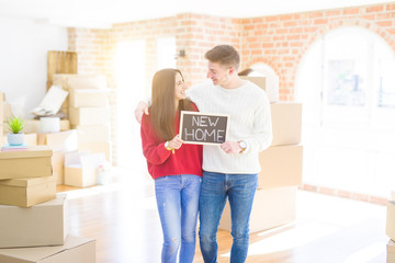 Beautiful young couple hugging in love and holding blackboard moving to a new home, smiling happy for new apartment