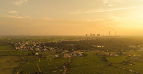 Aerial view of coal power plant - Sunrise near green agriculture field with factories outside the...