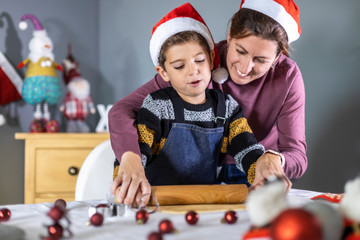 Little child and his mother making cookies on Christmas Day