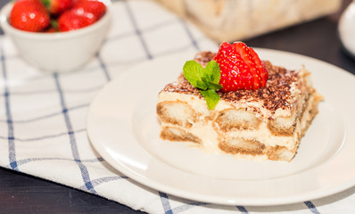 gourmet tiramisu dessert with strawberries in a beautiful plate on a dark background