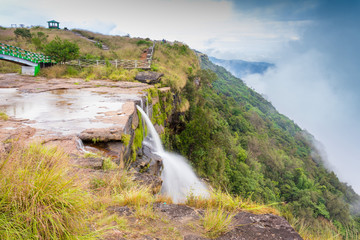 The beautiful white stream of water falling in the valley from the slope of lush green mountain...