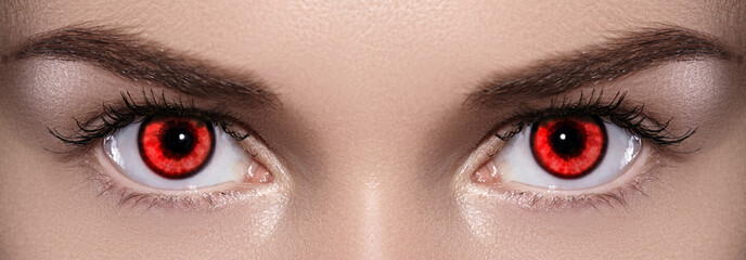 Close-up of Woman Eyes. Halloween Makeup. Devil, Vampire or Monster Eye Lens. Luminous Red Eyes - obrazy, fototapety, plakaty