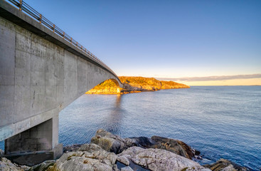 view of the long bridge over the sea to the island on a sunny warm autumn morning at sunrise