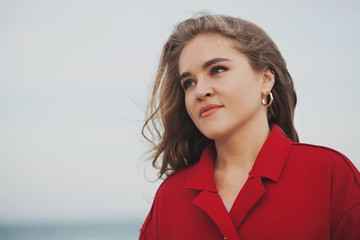 Beautiful woman in red coat walking on the beach