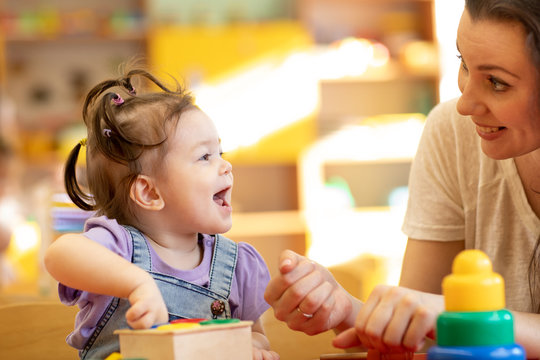 Mom Or Teacher And Baby One Year Ago Playing Logical Toys In Nursery