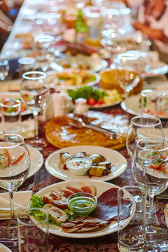 A Group Of People At A Long Table With Food. The Concept For The Joint Celebration Of Memorable Dates Or Holidays