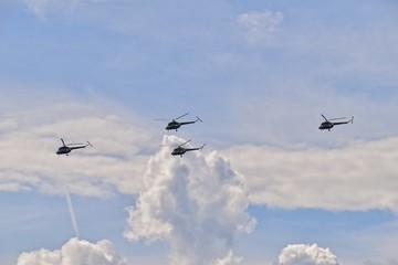 flying combat helicopters against a blue sky with clouds on a sunny day