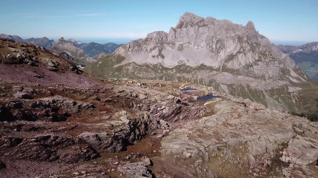 A reverse flyover of dry rocky mountains in Switzerland during the day.