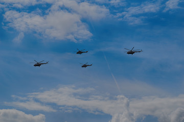flying combat helicopters against a blue sky with clouds on a sunny day