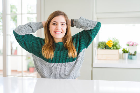 Young beautiful plus size woman wearing casual striped sweater relaxing and stretching, arms and hands behind head and neck smiling happy