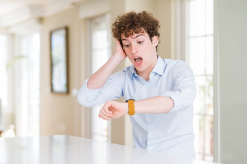Young business man with curly read head Looking at the watch time worried, afraid of getting late