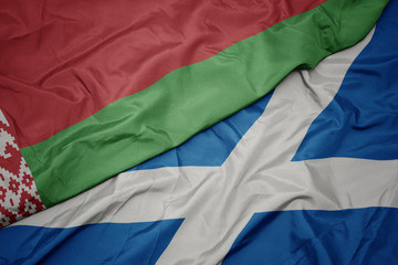 waving colorful flag of scotland and national flag of belarus.
