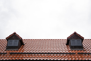 Roof with terracotta tiles on a background of cloudy gray autumn rainy sky. autumn mood. Cold tone. Rainy day. Horizontal orientation.