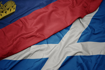 waving colorful flag of scotland and national flag of liechtenstein.