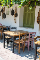 Front view of small cafe exterior. Table and empty chairs outdoor near the white wall. Tourist places. Typical Mediterranean restaurant, a place holidays in the summer