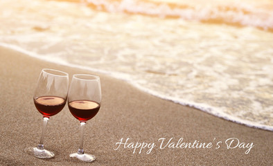 Two wine glasses on sand.