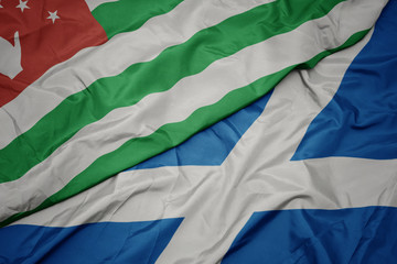 Obraz premium waving colorful flag of scotland and national flag of abkhazia.