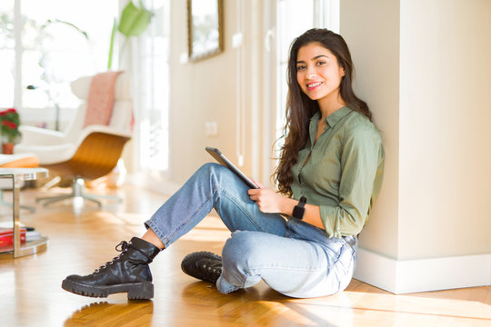 Beautiful young woman working using touchpad tablet sitting on the floor