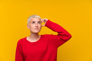 Teenager girl with white short hair over yellow wall having doubts and with confuse face expression