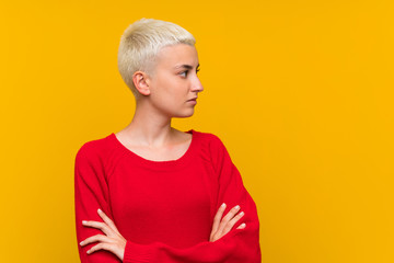 Teenager girl with white short hair over yellow wall standing and looking side