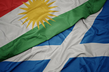 waving colorful flag of scotland and national flag of kurdistan.