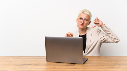 Teenager girl with short hair with a laptop showing thumb down