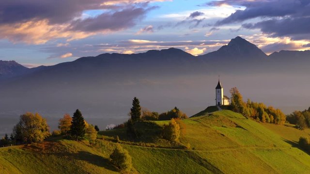 Aerial view of landscape of church of St. Primoz near Jamnik, Slovenia and Julian Alps at background