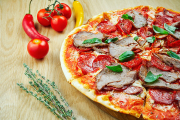 Italian, homemade pizza with meat, salami and hot pepper on a wooden table. Top view food with copy space. Flat lay