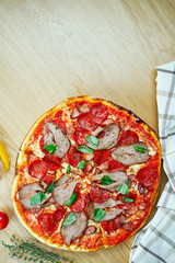 Italian, homemade pizza with meat, salami and hot pepper on a wooden table. Top view food with copy space. Flat lay