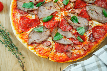 Italian, homemade pizza with meat, salami and hot pepper on a wooden table. Top view food with copy space. Flat lay