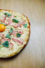 Italian, homemade carbonara pizza with yolk and bacon on a wooden table. Top view food with copy space. Flat lay