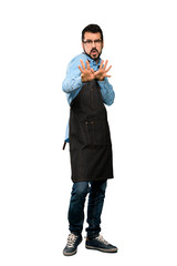 Full-length shot of Man with apron nervous stretching hands to the front over isolated white background